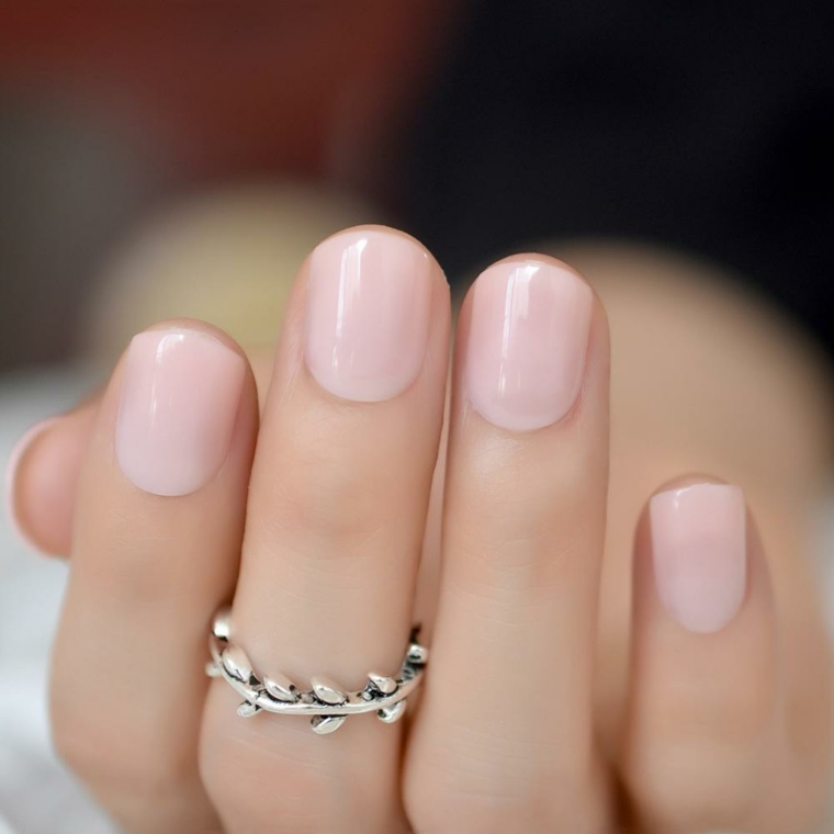 Unghie di colore rosa tenue, manicure con unghie corte, anello in oro bianco