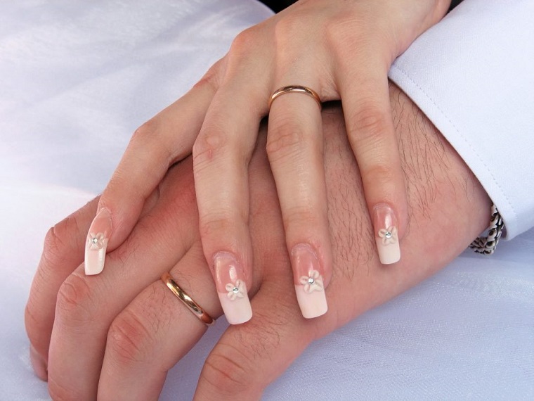 Mani uomo e donna con anelli in oro, unghie gel particolari, decorazioni manicure con piccoli brillantini e disegni floreali 