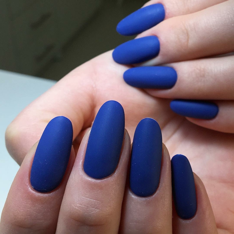 Smalto mat di colore blu, unghie lunghe a forma di mandorla per una donna con la carnagione chiara 
