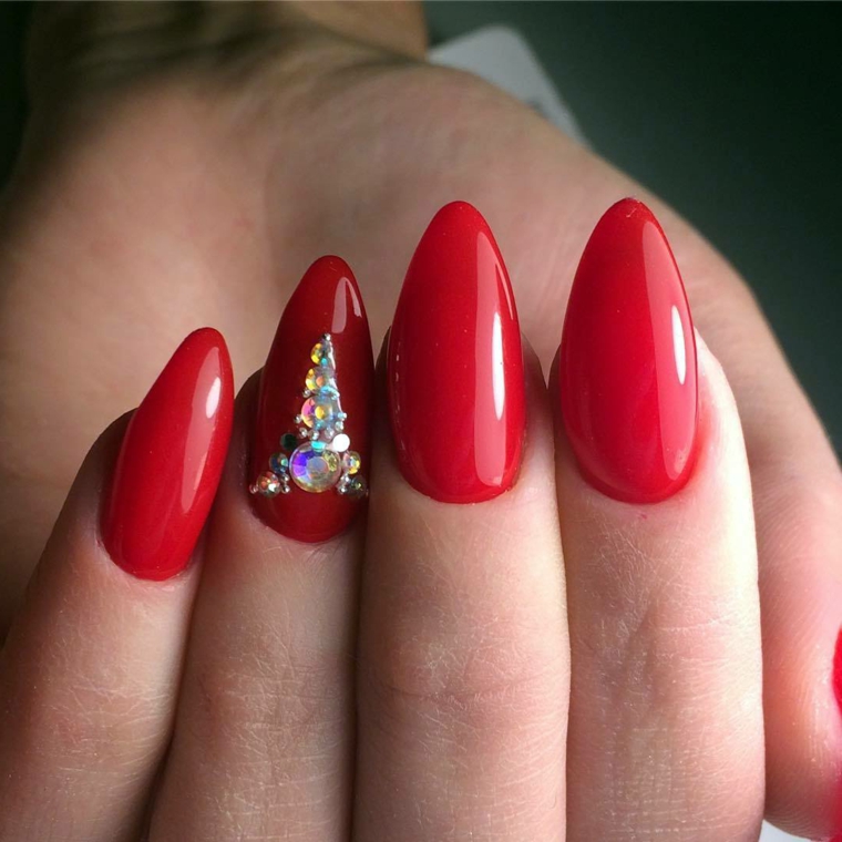 Smalto di colore rosso con riflessi, decorazione con brillantini sull'unghia del dito anulare 