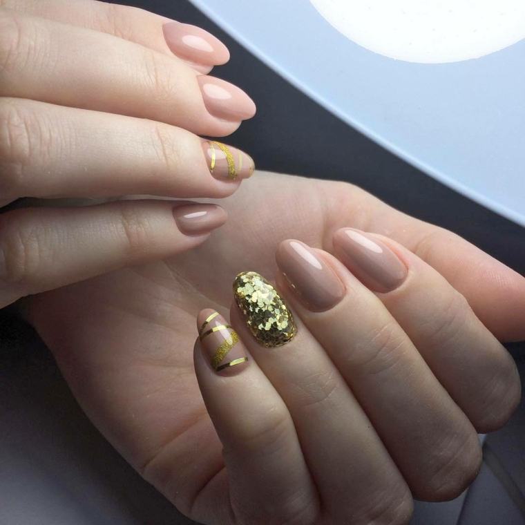 Accent nail sull'unghia del dito anulare con pailettes color oro e nastri sul mignolo su una base smalto beige 