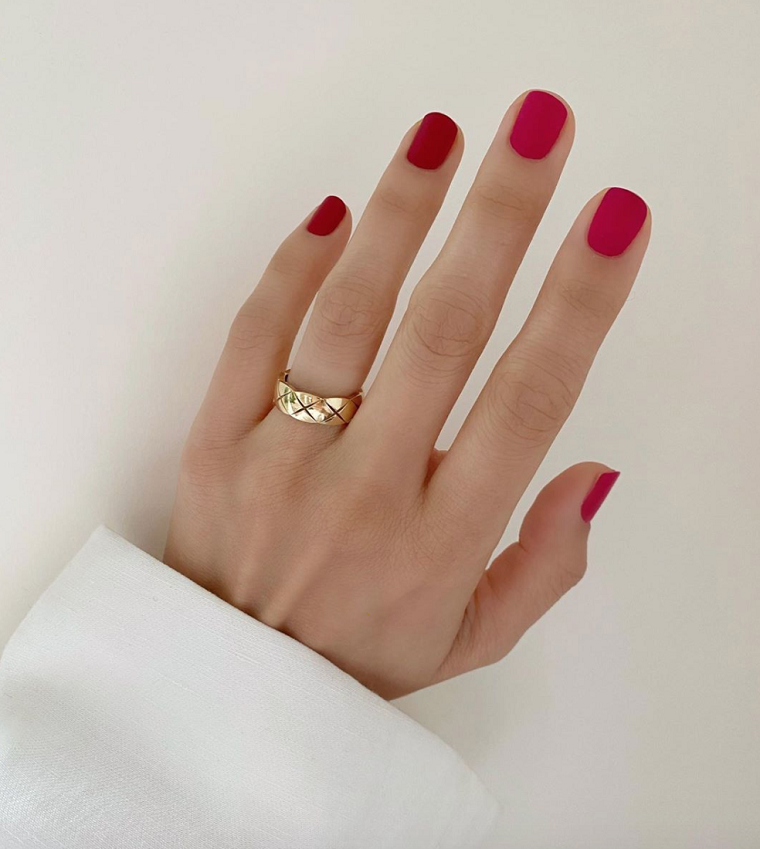 mano donna con smalto di colore rosso anello in oro unghie forma quadrata corte