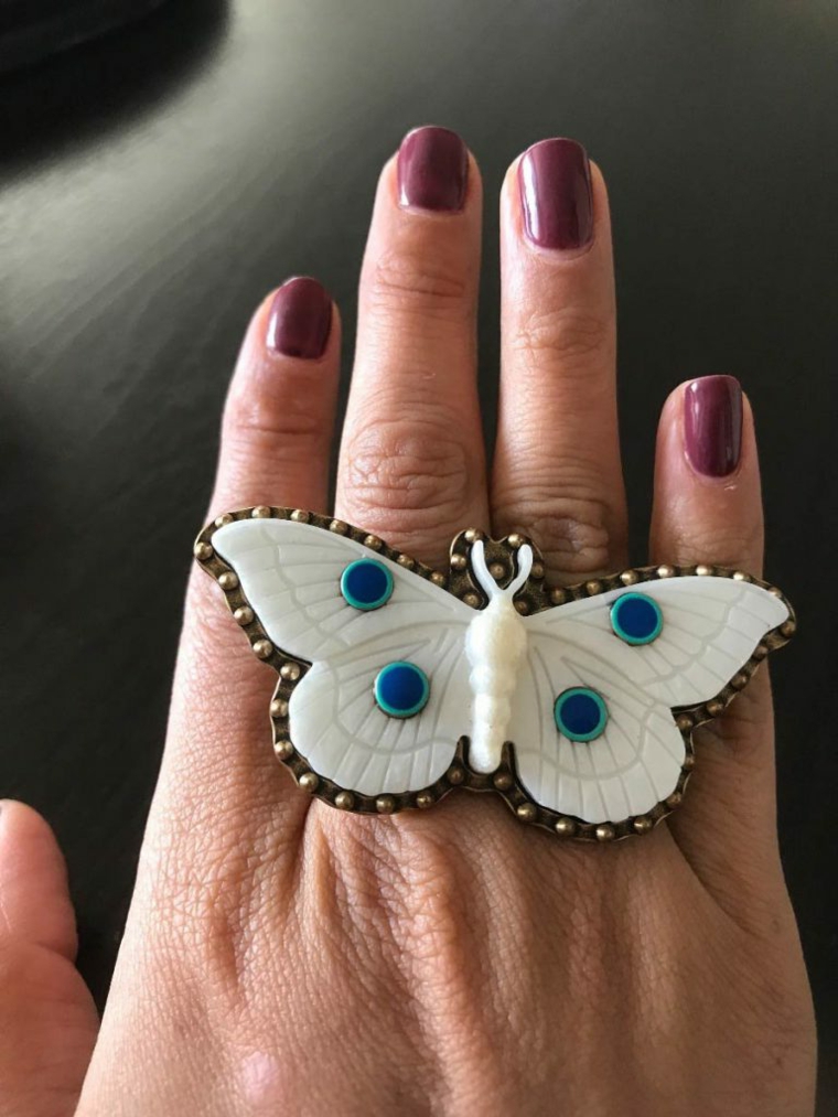Smalto di colore viola, anello forma farfalla, mano di una donna