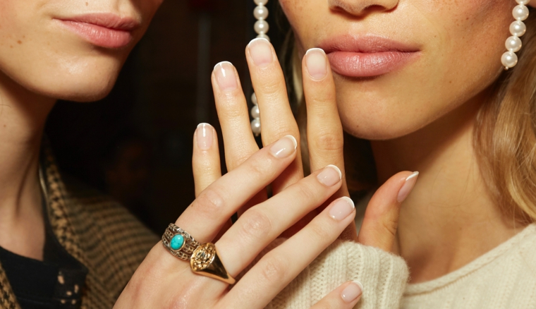 mani di due donne unghie corte con french manicure dita con anelli