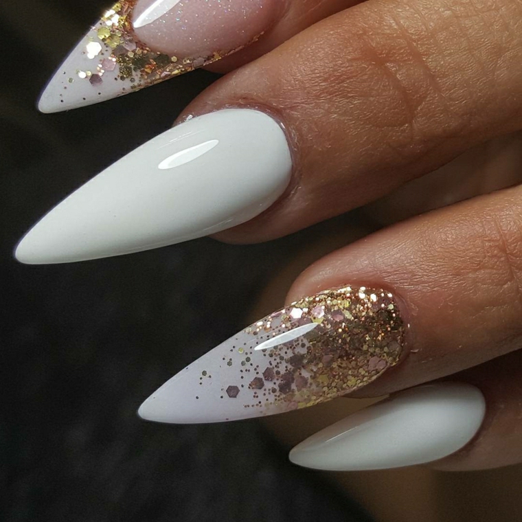 Forma delle unghie a stiletto di colore bianco e accent nail oro glitter sull'anulare e l'indice 