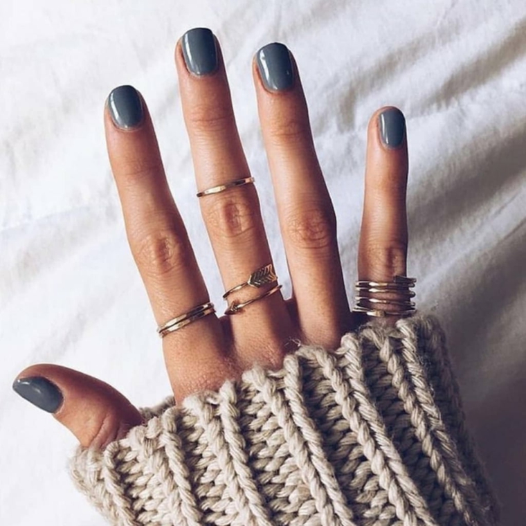 Anelli sulle dita, smalto di colore grigio, maglione di lana 