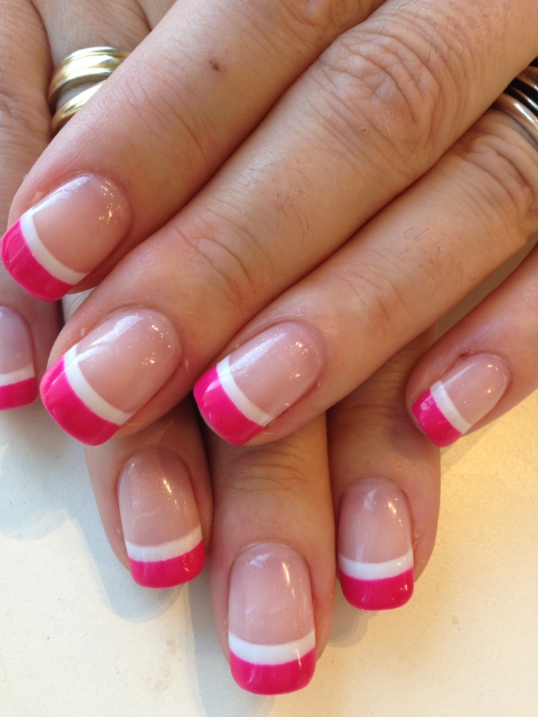 una proposta di manicure french colorato con smalto rosa ciliegia e riga bianca su base trasparente