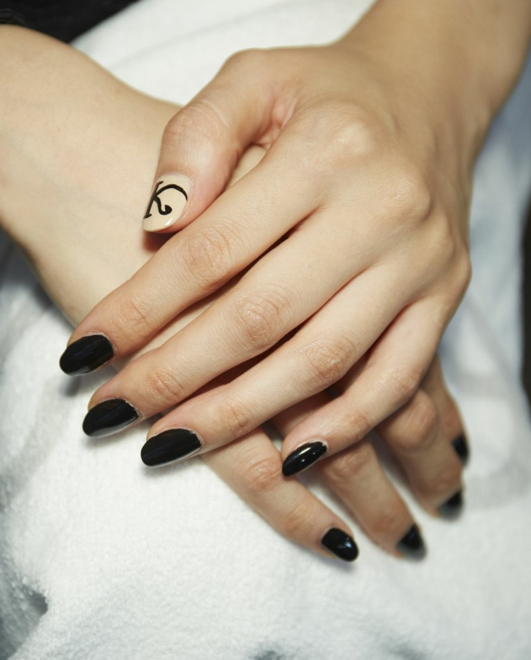 Manicure unghie corte, smalto di colore nero, accent nail colore beige, disegno lettera K