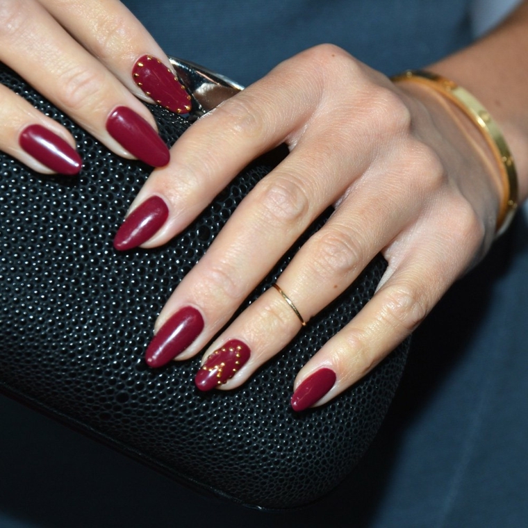 nail art rosso, una manicure giovane e di tendenza con borchiette oro