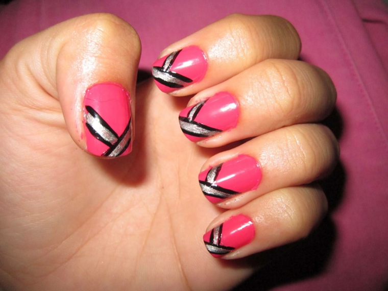 manicure colorata realizzata con uno smalto di una nuance di rosa acceso e decorazioni in nero e argento