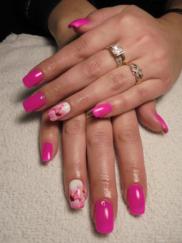 smalto rosa, una manicure realizzata con una nuance tendente al fucsia e anulare bianco con dei fiori