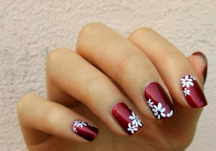 unghia rosse, una proposta di manicure delicata e romantica grazie a dei fiori bianchi