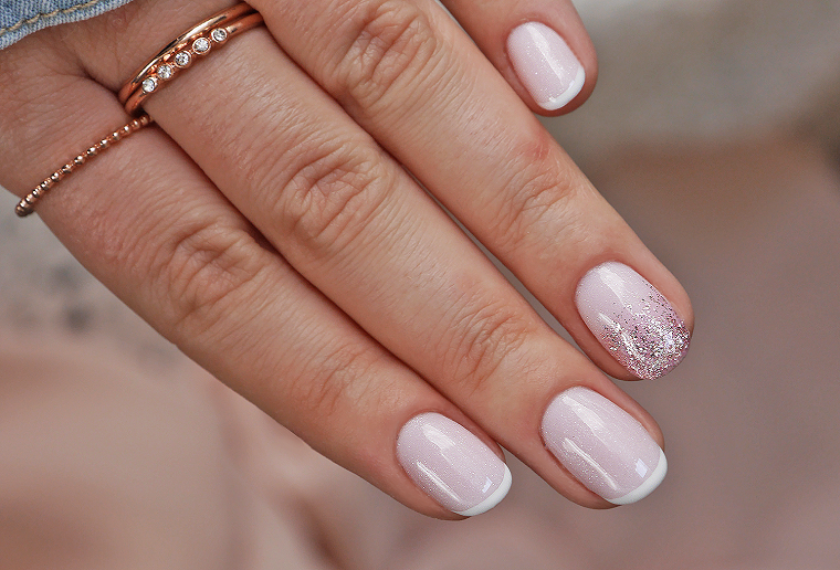 manicure con smalto rosa lucido accent nail argento anelli sulla mano di una donna